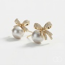 Close up of the pave bow and pearl drop on a plain white ground, with the stud post visible