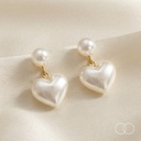 The pair hanging on cream silk, showing how the heart sits below the pearl