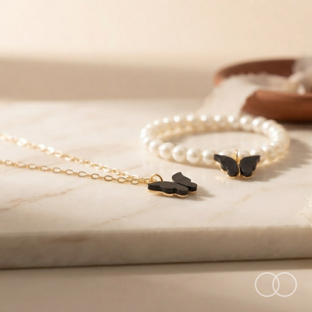 The butterfly necklace and the pearl bracelet on a marble surface