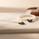 The butterfly necklace and the pearl bracelet on a marble surface