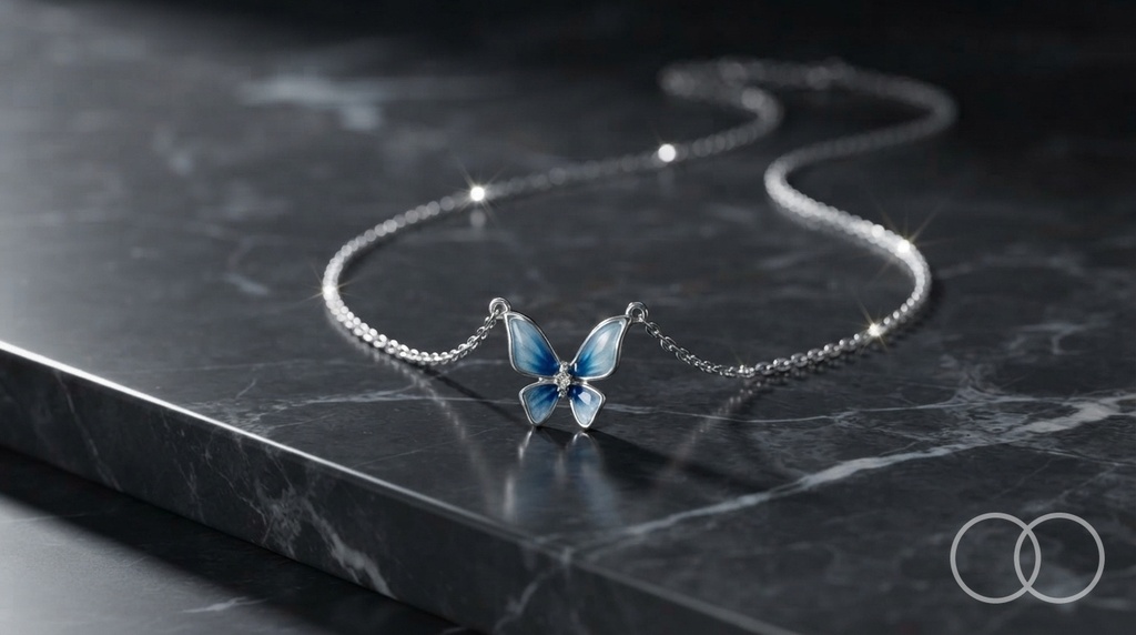 The butterfly pendant and chain laid out on black marble