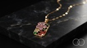 The Garden Panel pendant resting on black marble with the gold lip chain