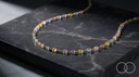 The Rainbow Bead necklace curved across a black marble slab