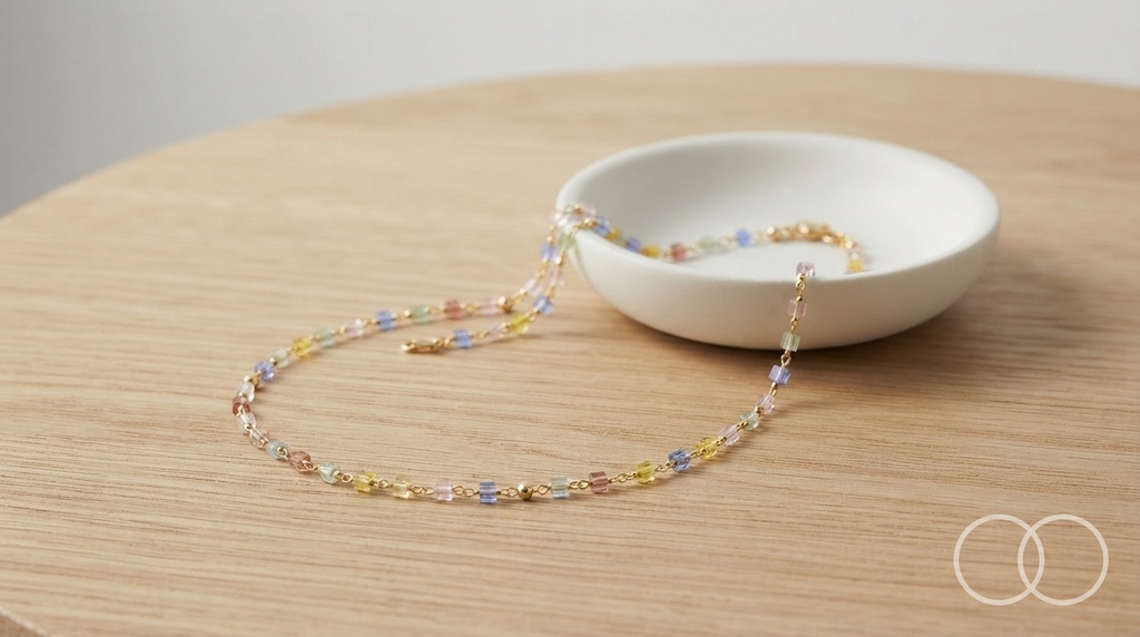 The Rainbow Bead necklace on a pale wood table beside a ceramic dish